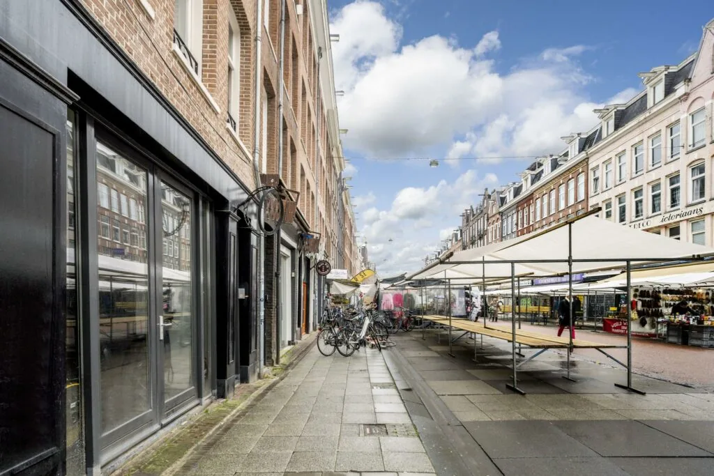 Marktkramen en winkels aan de Albert Cuypstraat in Amsterdam op een deels bewolkte dag.